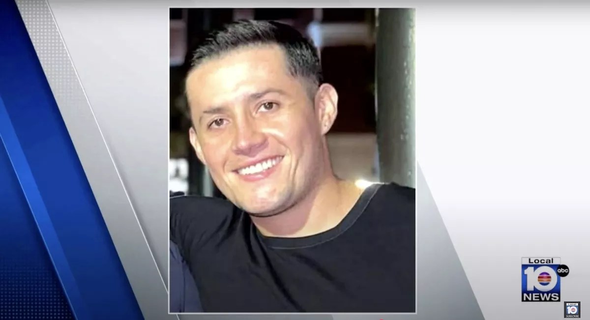 A young man in a black t-shirt smiles.