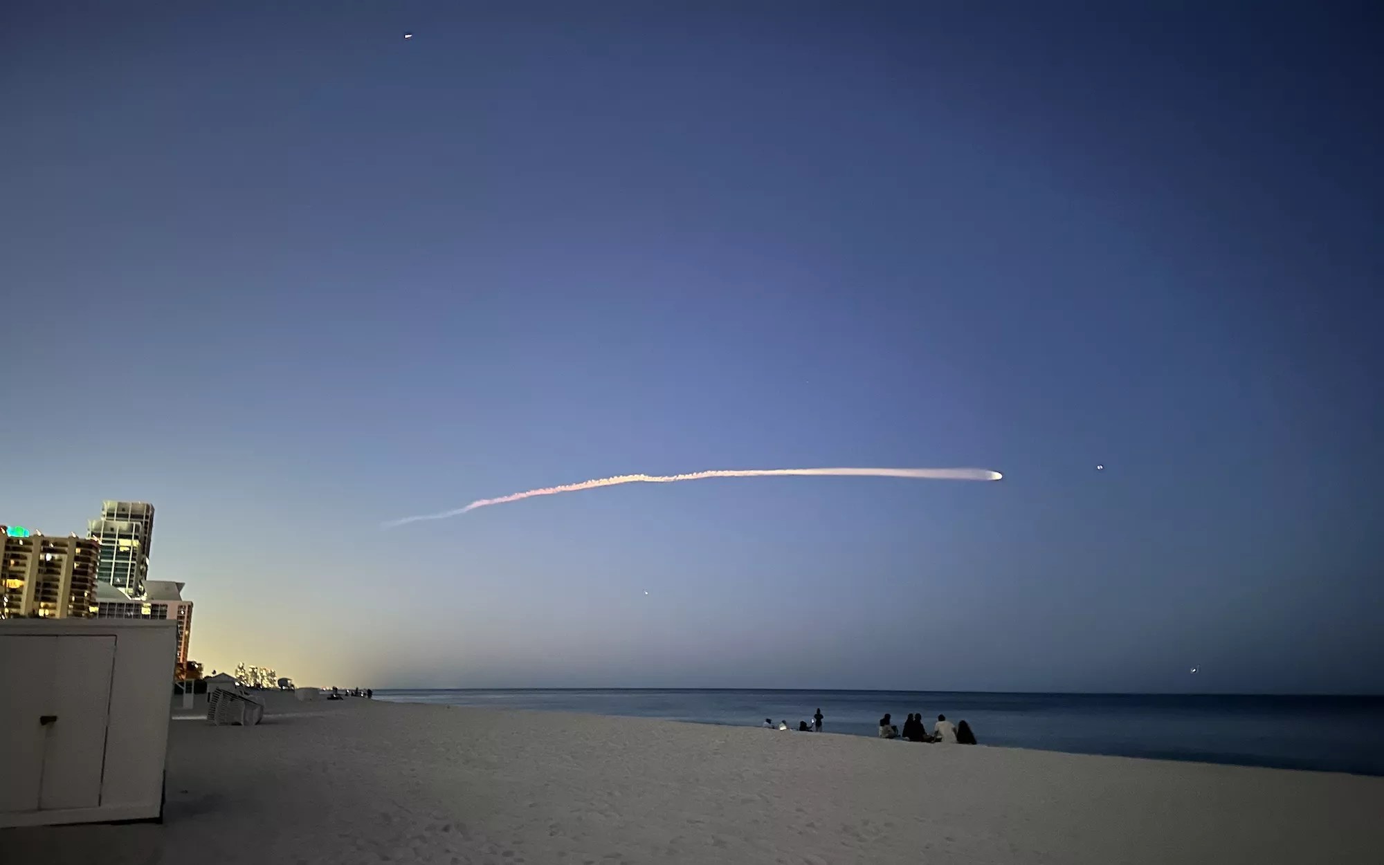 A SpaceX rocket streaking across the night sky, viewed from Miami Beach