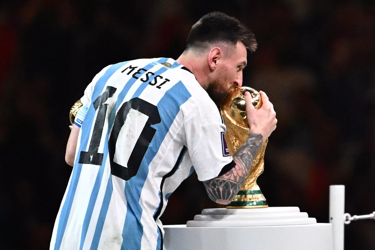 Soccer legend Lionel Messi kisses the World Cup trophy.